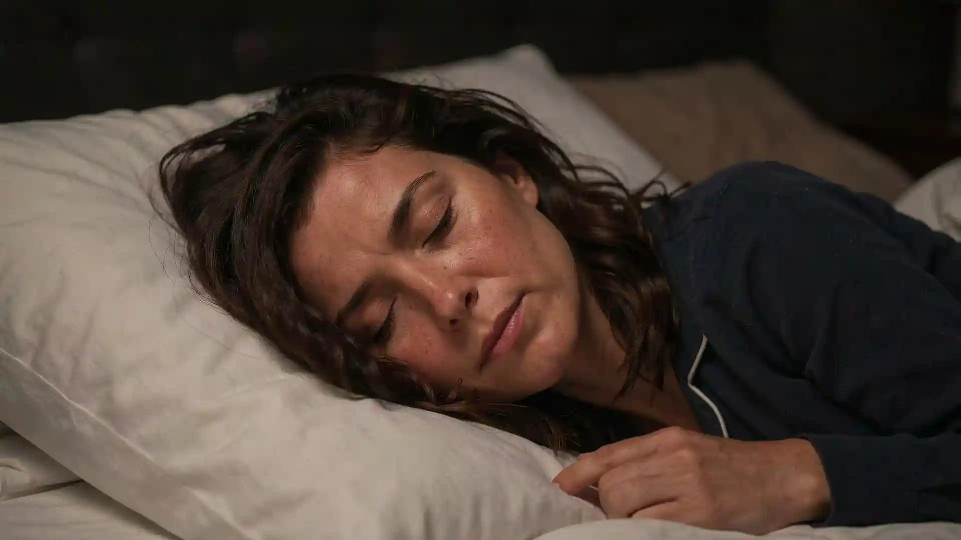 Sarah sleeping deeply and peacefully in a cozy dark bedroom